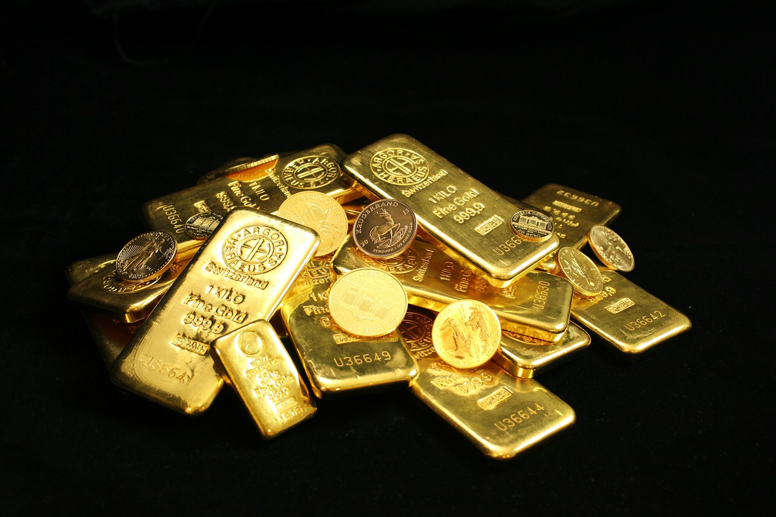 Pile of gold bars and coins on a black background